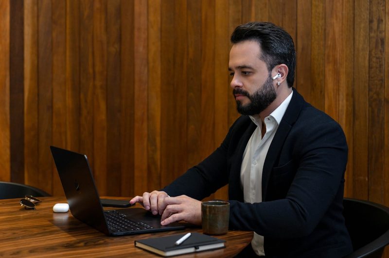 Felipe Ramalho concentrado diante do laptop, conferindo documentação de um imóvel.