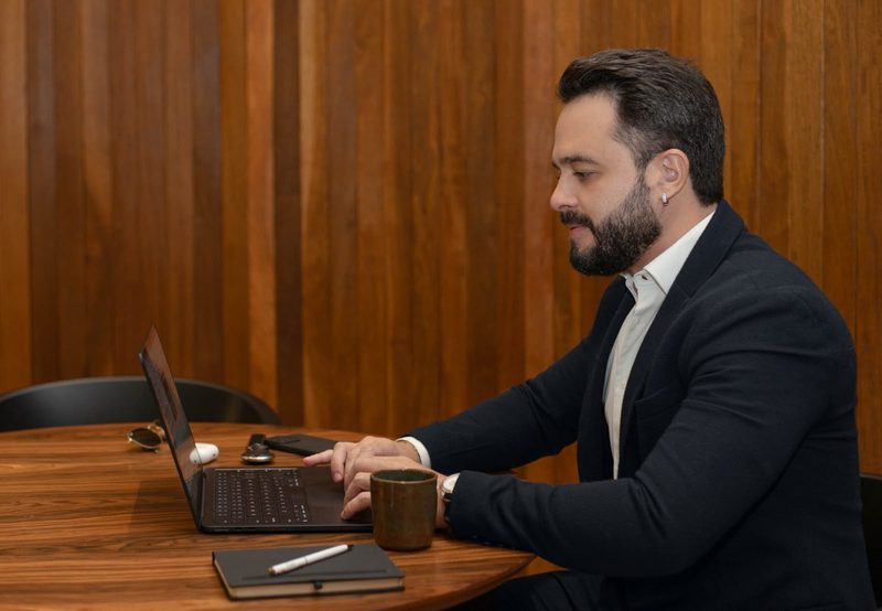 Felipe Ramalho concentrado, trabalhando em um laptop durante o levantamento e a negociação de um imóvel.