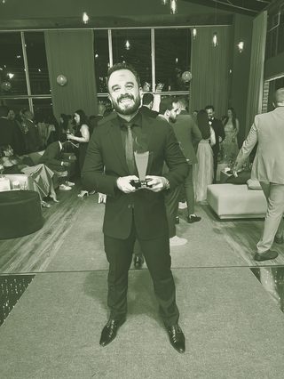 Felipe Ramalho recebendo um prêmio do setor imobiliário em uma cerimônia noturna.